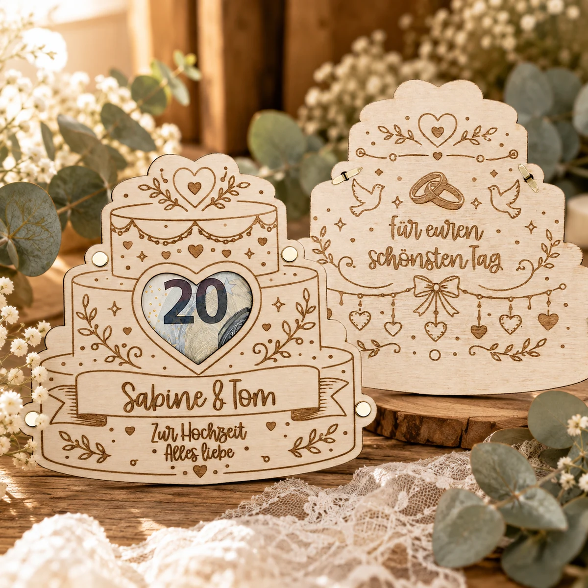 Geldgeschenk-Karte aus Holz in Form einer dreistöckigen Hochzeitstorte, ein Geldschein liegt sichtbar hinter dem Sichtfenster, darunter die Gravur mit den Namen des Brautpaars