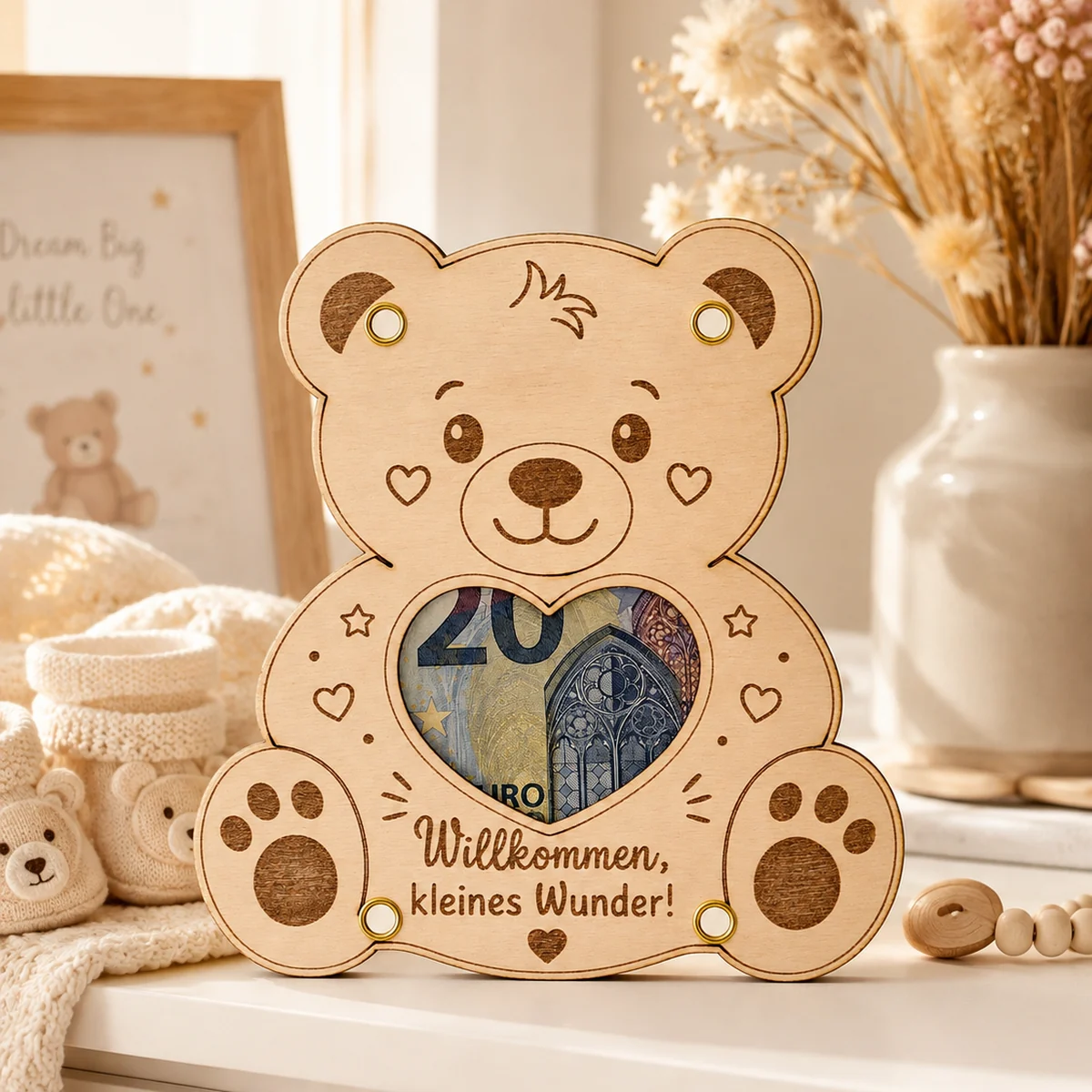 Geldgeschenk-Karte aus Holz in Form eines Teddybären, ein Geldschein liegt sichtbar hinter dem Herzfenster, darunter die Gravur „Willkommen, kleines Wunder!“