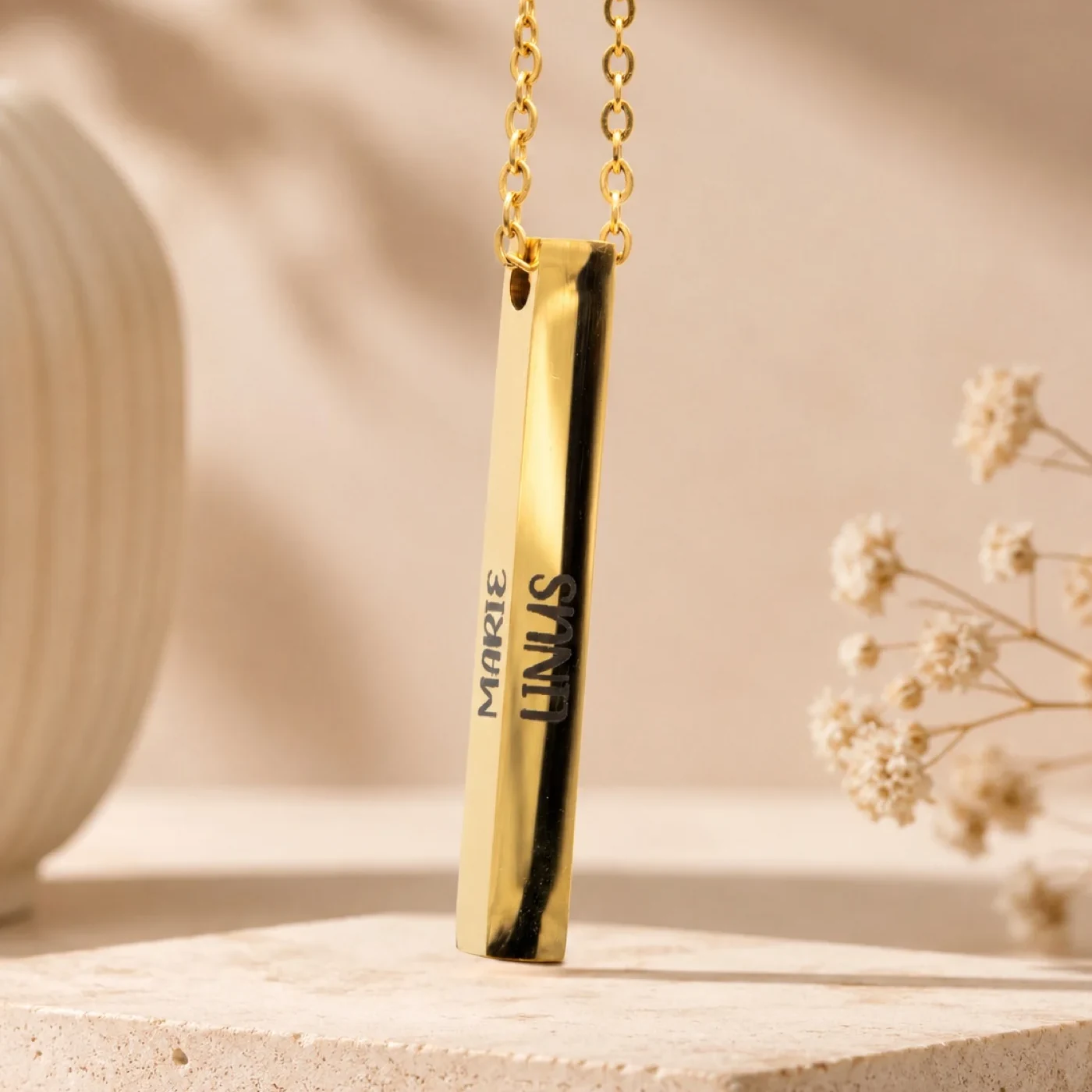 Goldene Stabkette mit Namensgravur, an einer Halskette getragen