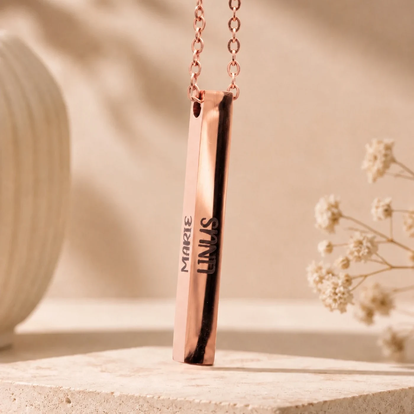 Roségoldene Stabkette mit Namensgravur, an einer Halskette getragen